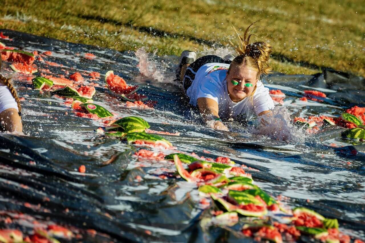 Person sliding on watermelon-covered tarp.