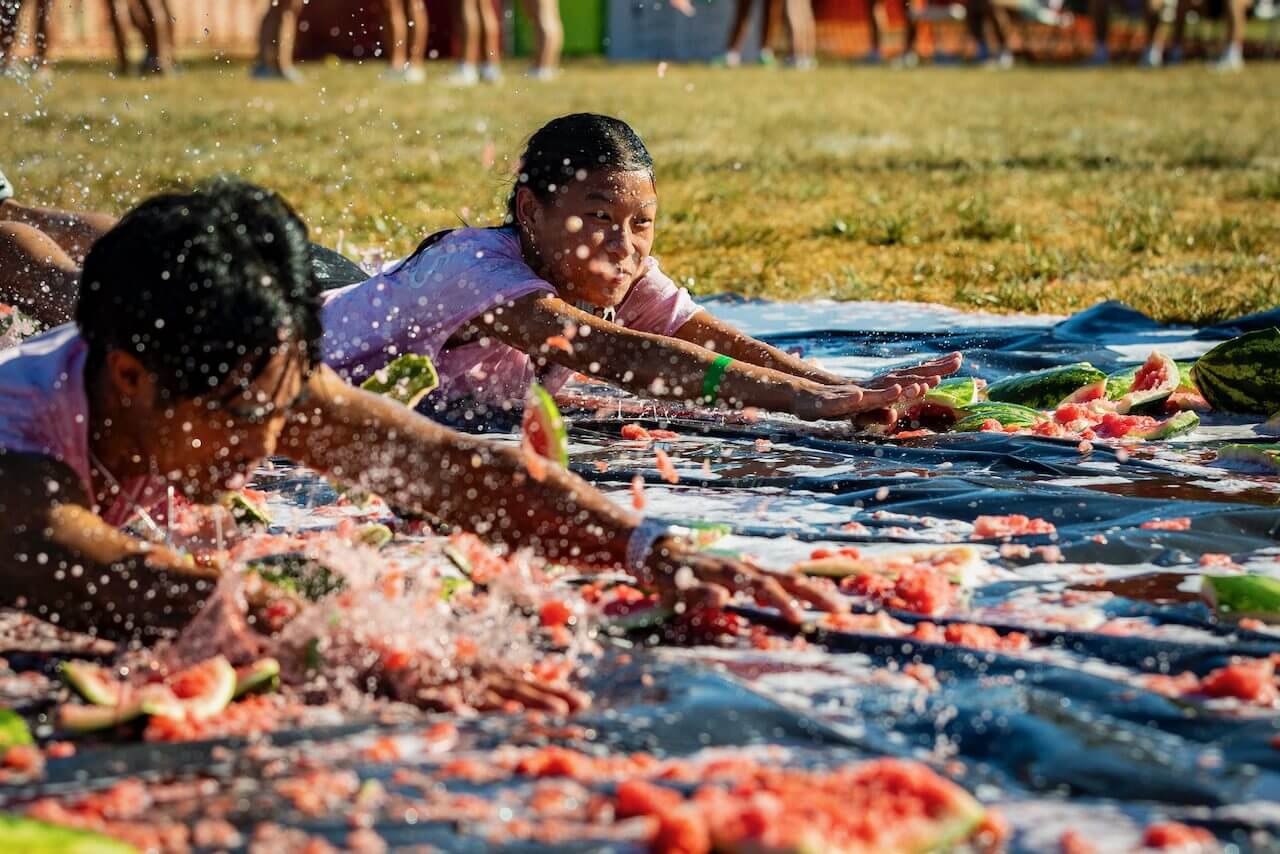People sliding through watermelon pieces outdoors.
