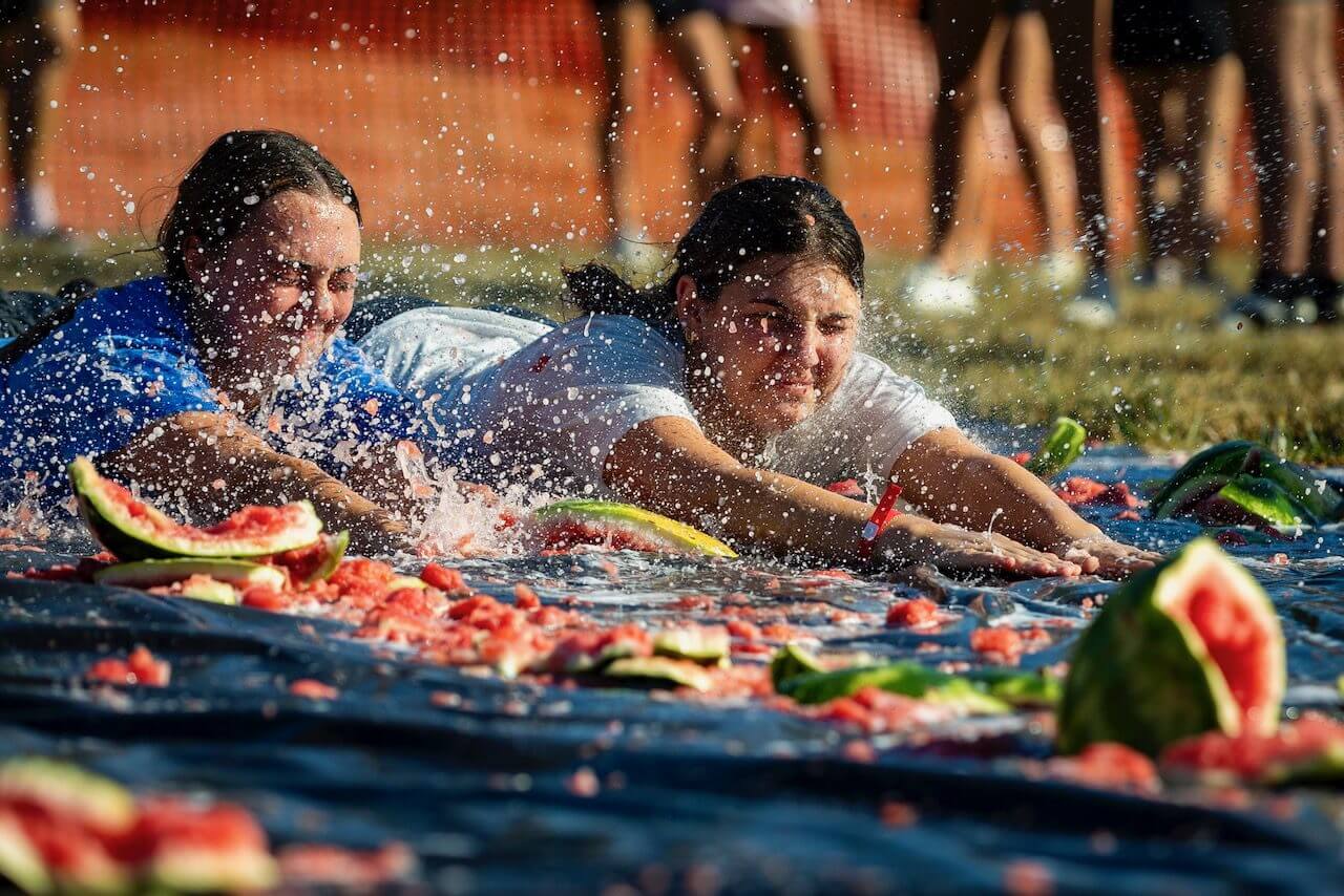 People sliding through smashed watermelon pieces.