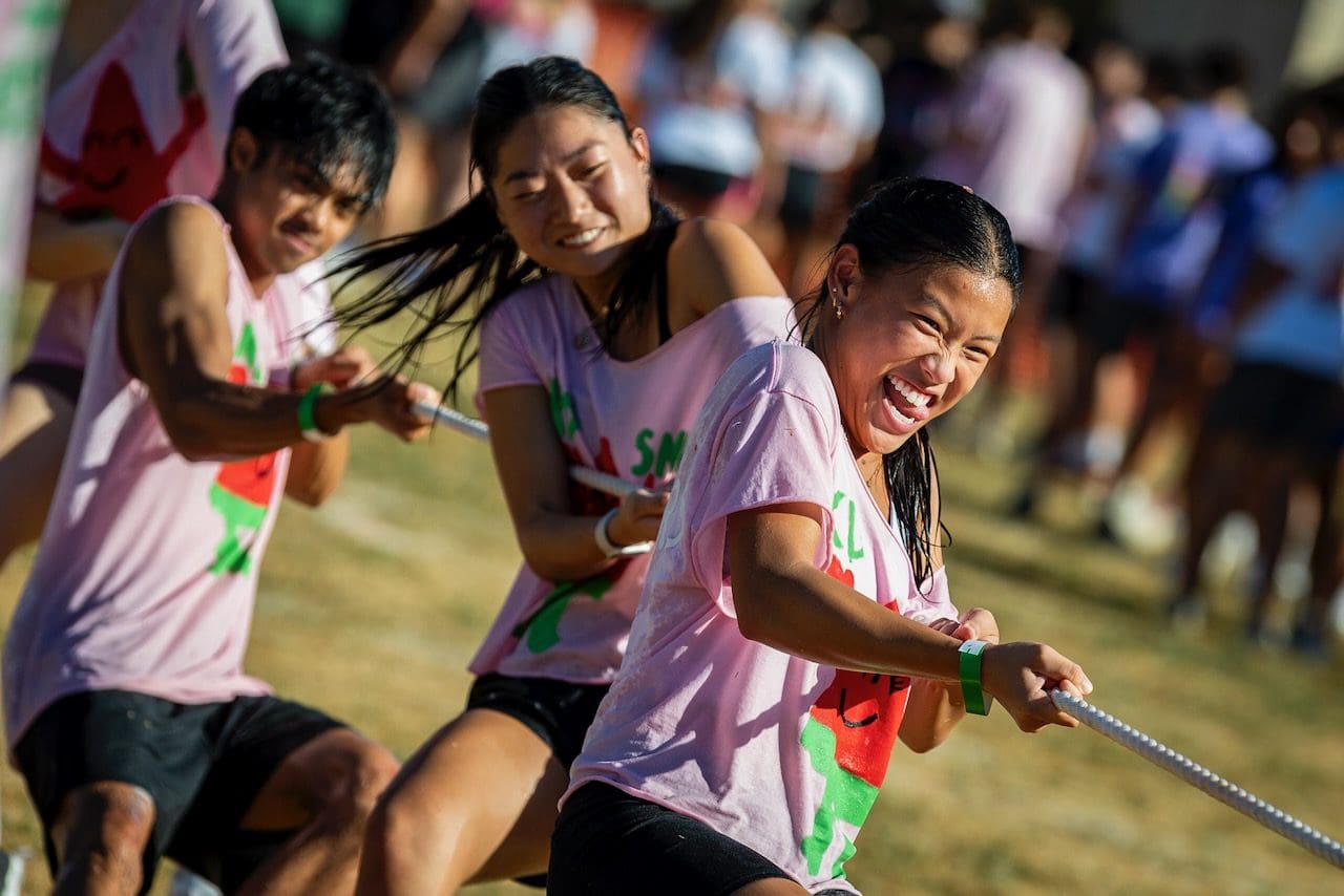 People enthusiastically playing tug-of-war outdoors.