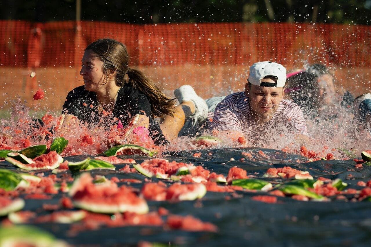 People sliding through smashed watermelons at festival.