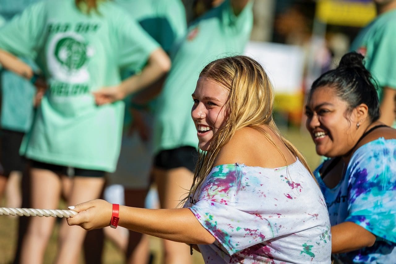 Two women joyfully participate in tug-of-war.