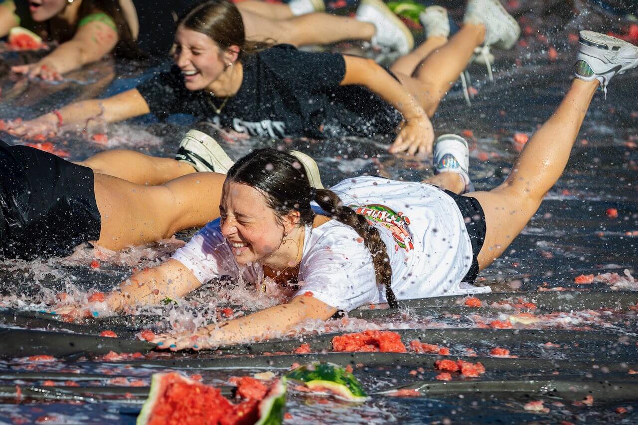People sliding on smashed watermelons, laughing joyfully.
