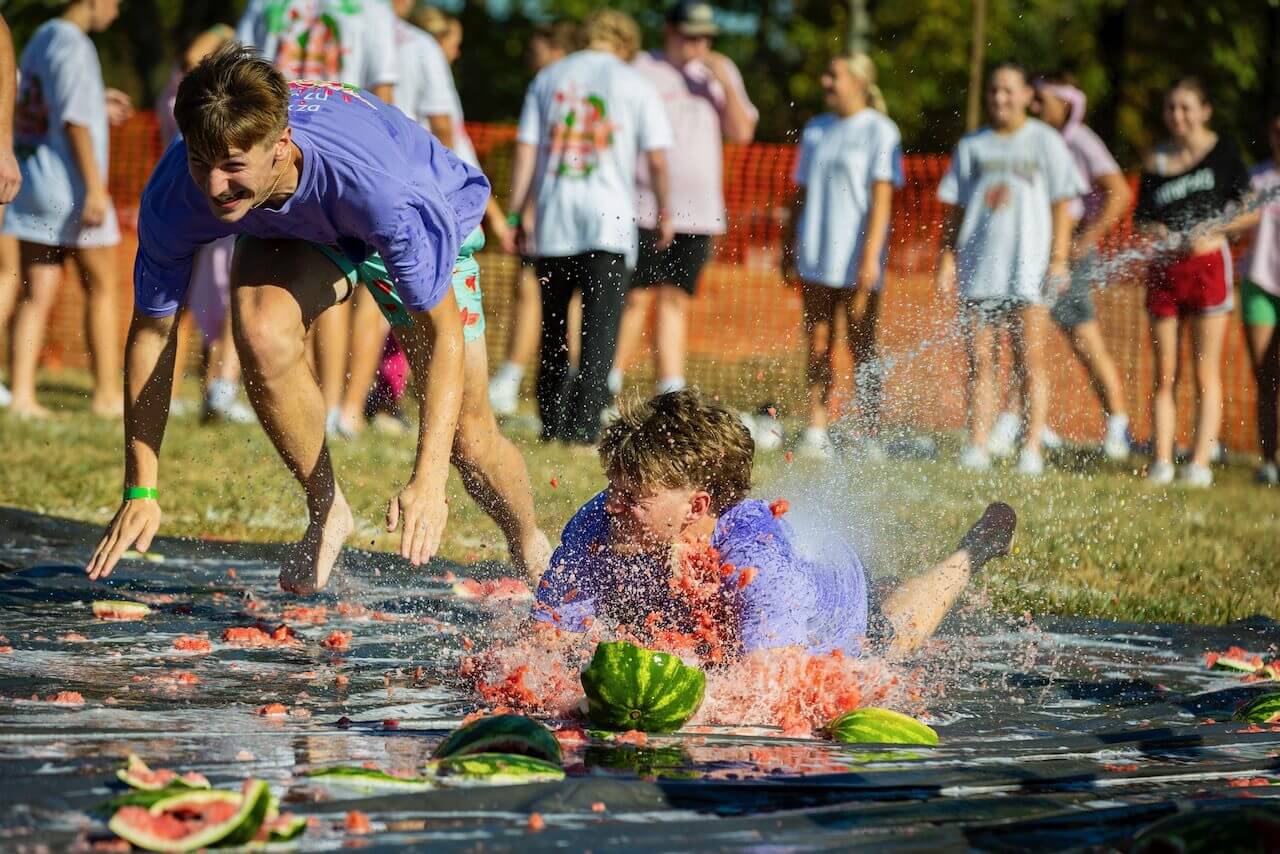 People playing on smashed watermelons outdoors.