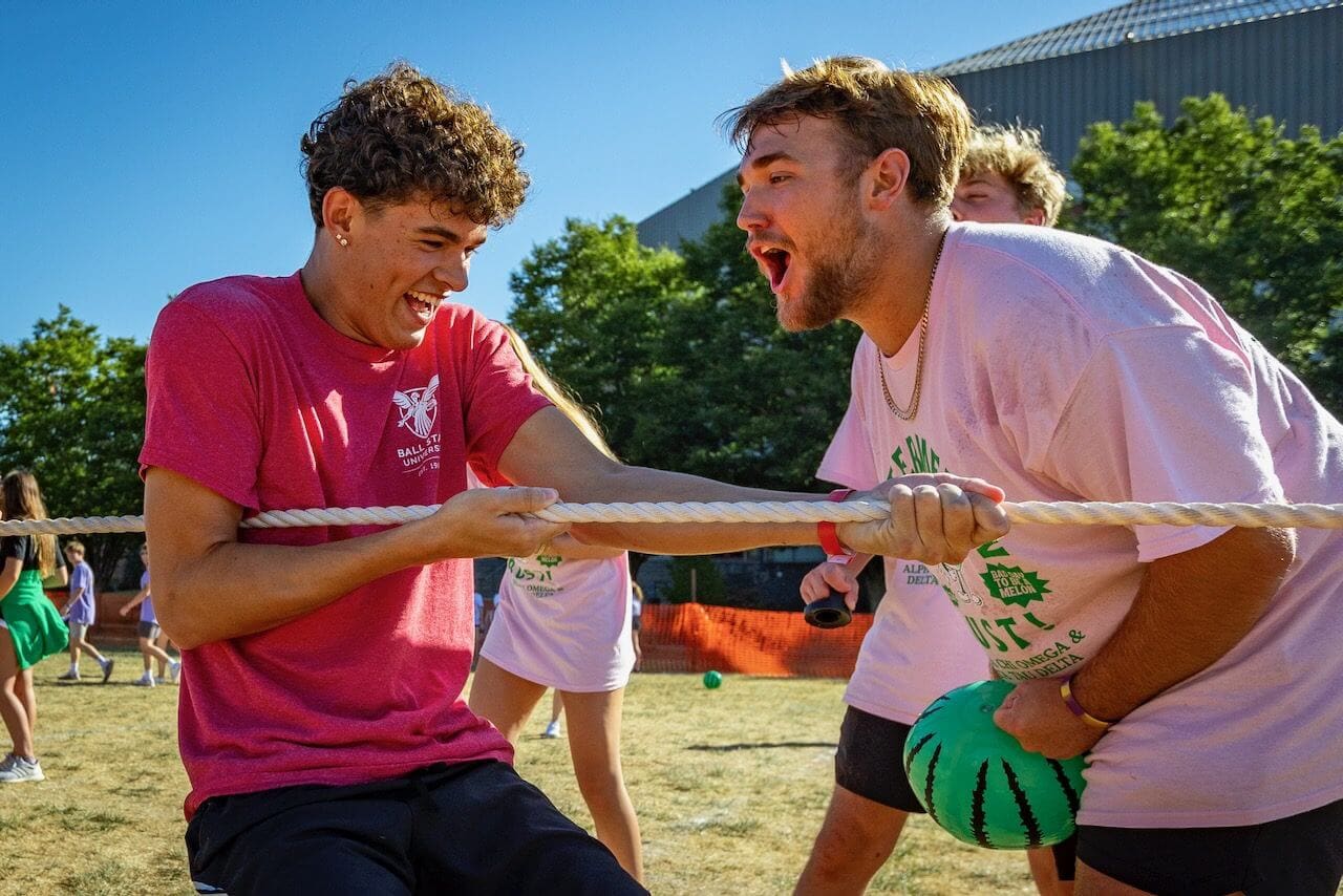 People playing tug-of-war outdoors, smiling.