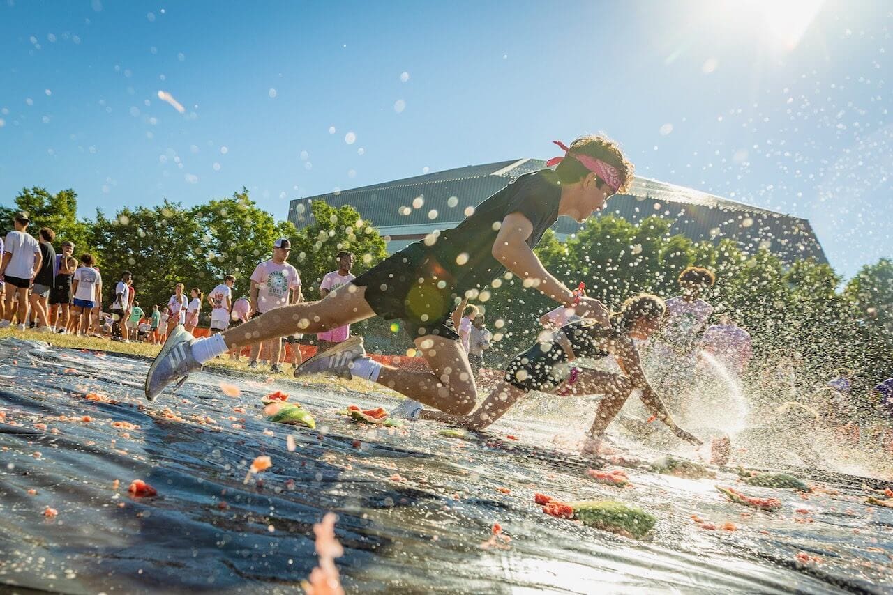 People sliding on tarp during outdoor event.