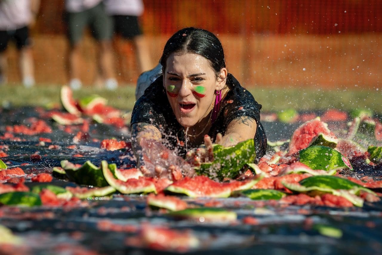 Person sliding on watermelon-covered tarp.
