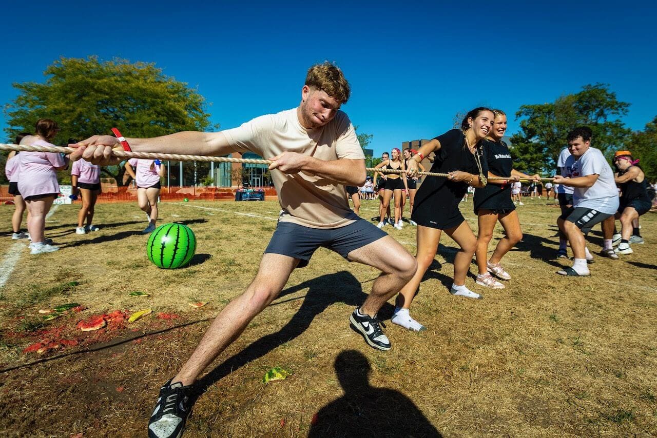 People playing tug-of-war outdoors, sunny day.