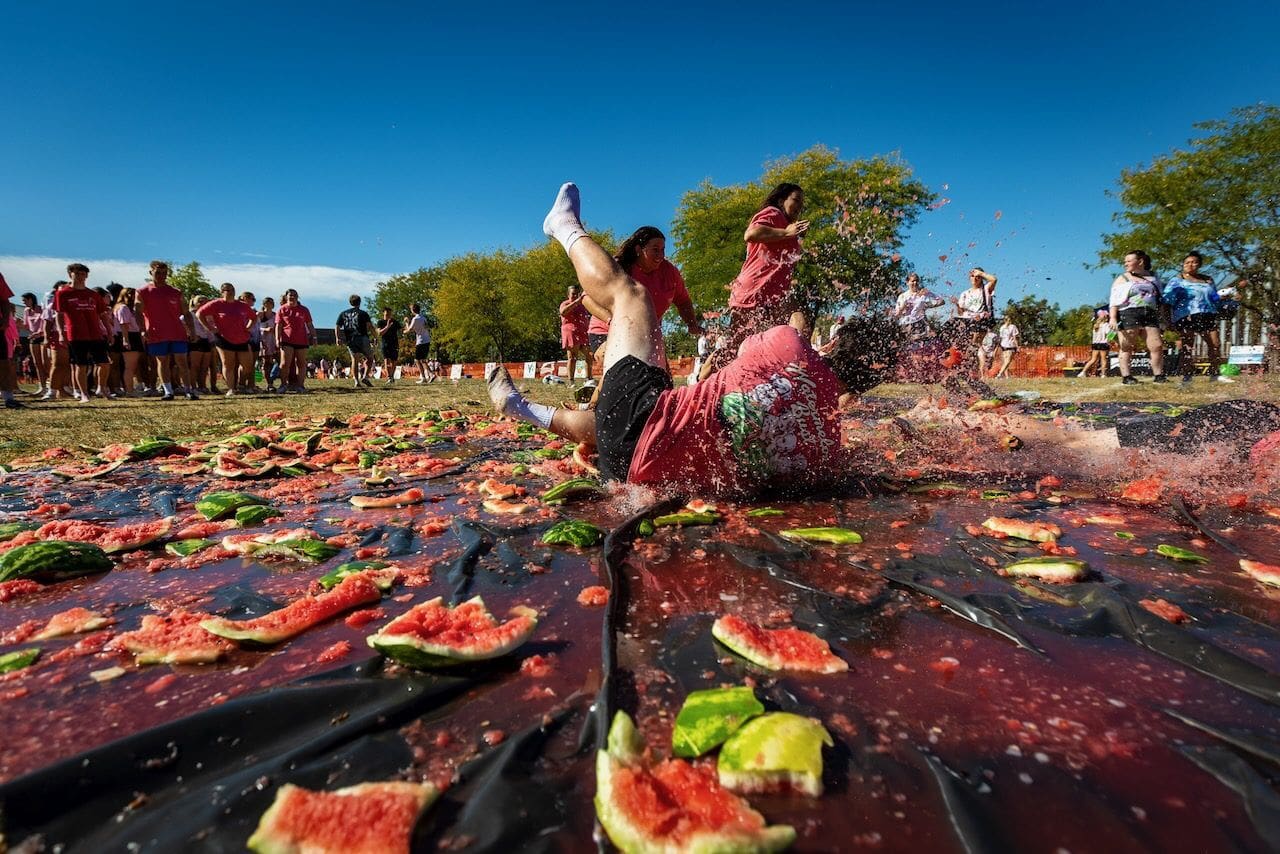 People slipping on watermelon-covered field.