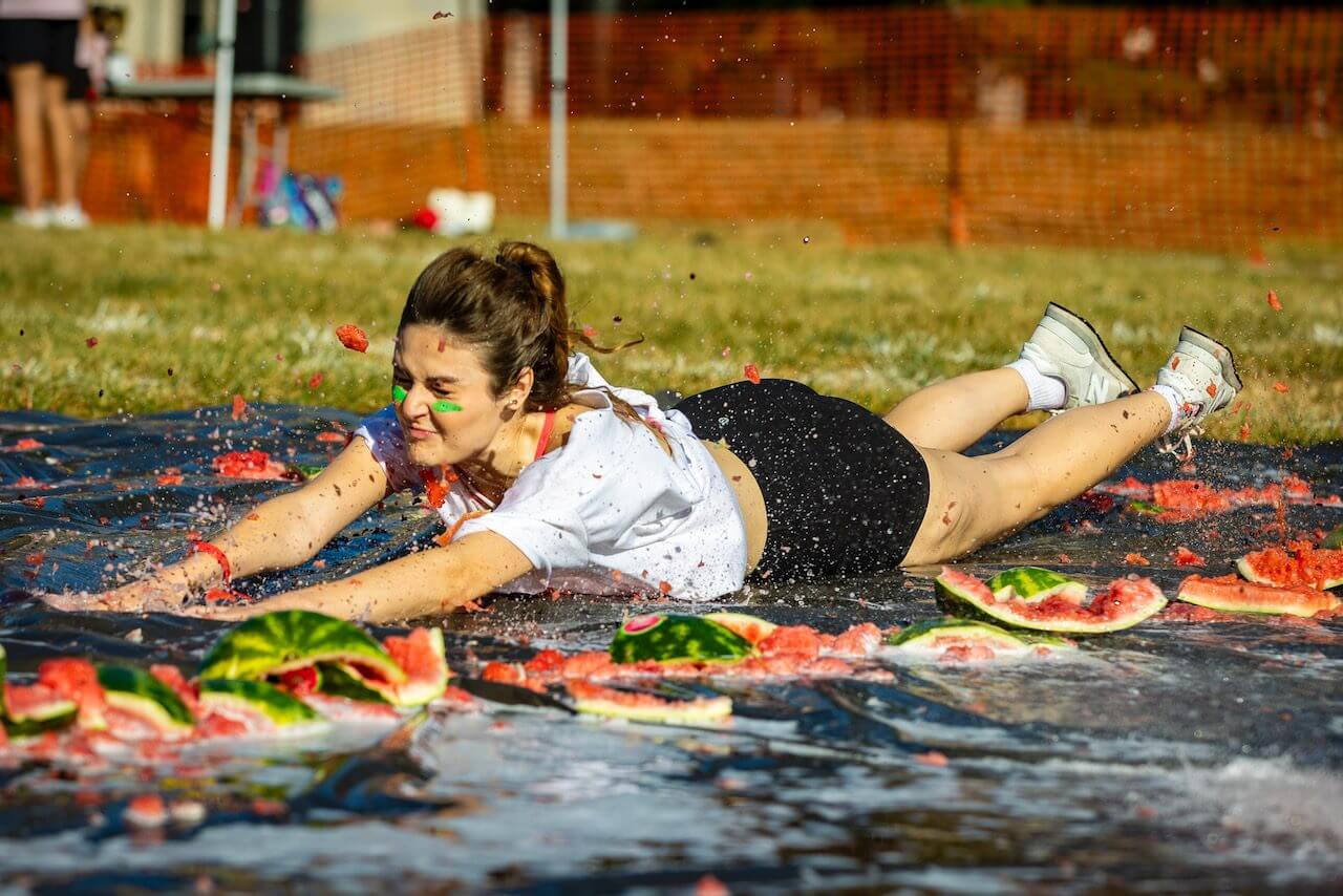 Person sliding through smashed watermelons on grass.