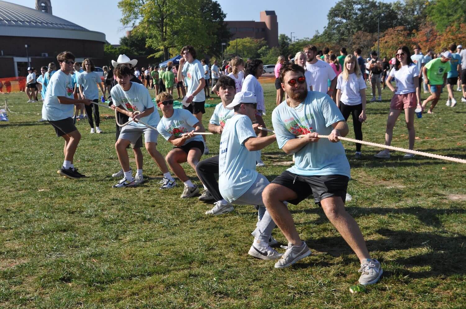 Group playing tug-of-war outdoors on grass.